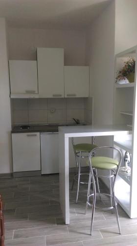 a kitchen with white cabinets and a table and chairs at Comfortable Studio in Sumartin with Sea View - 22 m² in Sumartin