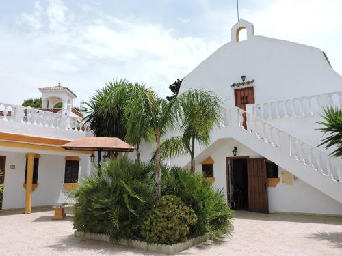 a white building with a palm tree in front of it at Spacious Villa in Conil de Frontera with Private Pool in Roche