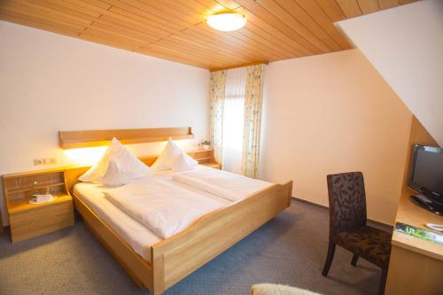 a bedroom with a bed and a desk and a television at Hotel-Restaurant & Metzgerei Rößle in Dettingen an der Erms