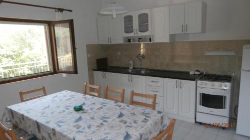 a kitchen with a table and a kitchen with white cabinets at Charming Apartment in Gdinj + Garden in Gdinj