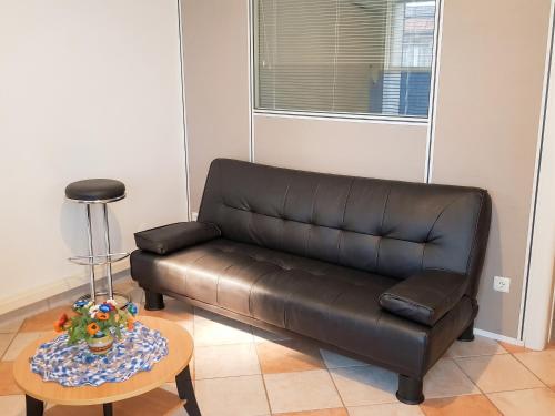 a brown leather couch in a living room with a table at Appartement confort au Diamant 25 m² terrasse in Le Diamant