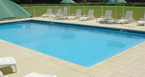 a large swimming pool with chairs and a group at Maison de charme à Saint-Vincent-la-Châtre avec piscine partagée in Saint-Vincent-la-Châtre