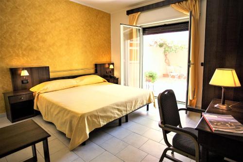 a bedroom with a bed and a table and a window at Hotel Marabel in SantʼAlessio Siculo