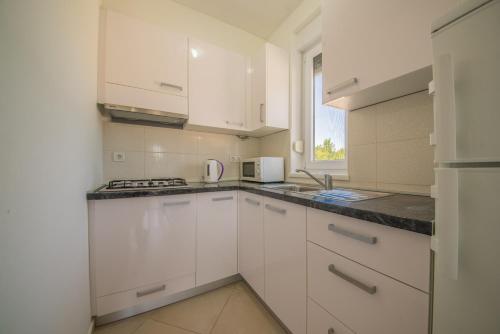 a white kitchen with white cabinets and a window at Bright Apartment in Vrsi with Terrace and Garden, 65 m² in Vrsi