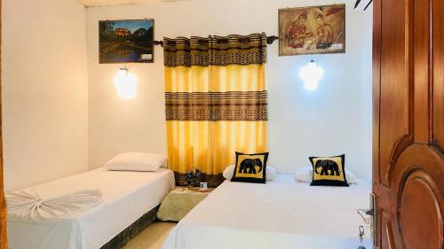 a room with two beds and a window at The Nilmini Lodge in Sigiriya