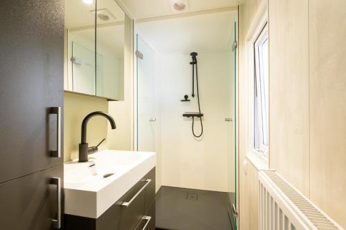 a white bathroom with a sink and a shower at De Bosvlinder in Hoenderloo