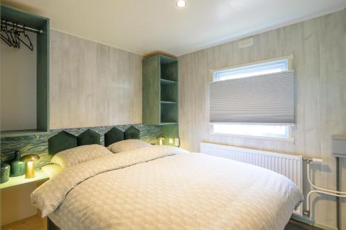 a bedroom with a large white bed with a window at De Bosvlinder in Hoenderloo