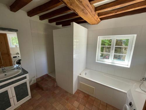 a bathroom with a tub and a sink and a window at Cottage Normand in Lison