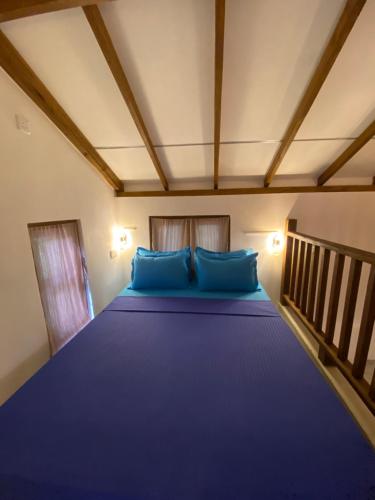 a bedroom with a large bed with blue pillows at Starfish Cabbana in Arugam Bay