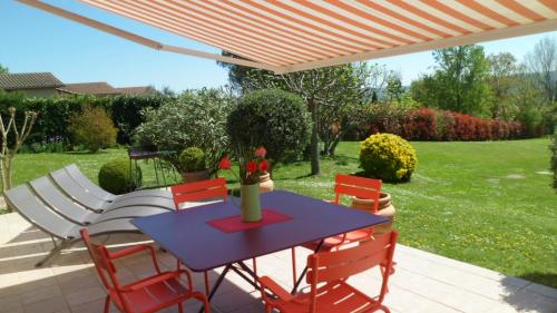 a table and chairs under an umbrella on a patio at Maison au charme champêtre - Monlaur-Bernet in Monlaur-Bernet