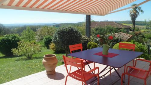 a patio with a blue table and red chairs at Maison au charme champêtre - Monlaur-Bernet in Monlaur-Bernet