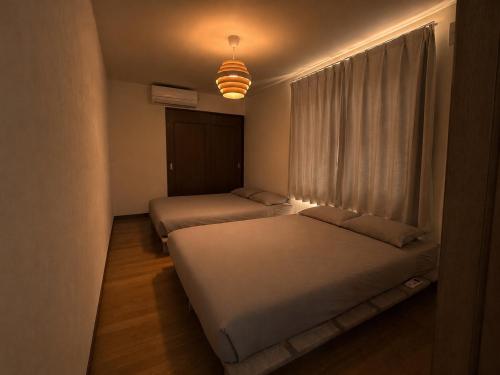 two beds in a small room with a window at 美瑛Stay in Biei