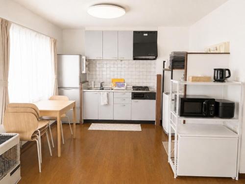 a kitchen with white cabinets and a table and a kitchen with a refrigerator at 美瑛Stay in Biei