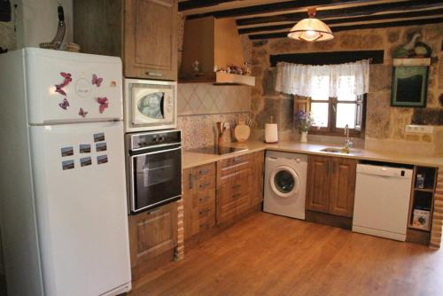 a kitchen with a white refrigerator and a dishwasher at Charming House in La Cavada with Jacuzzi in La Cavada