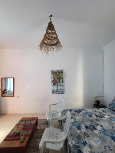 a bedroom with two white chairs and a bed at Dar Essadeg Bis in Tataouine