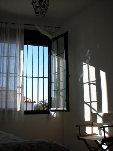 a bedroom with a window with a view of a building at Charming apartment with mountain view in Jabuguillo, 70 m² in Aracena