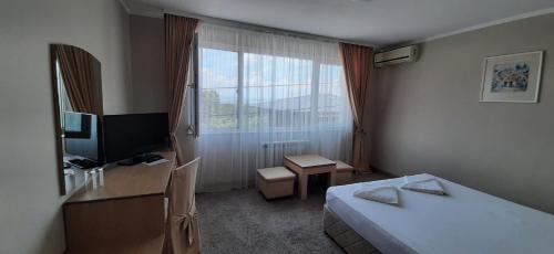 a hotel room with a bed and a desk and a window at Family Hotel Diana in Sofia
