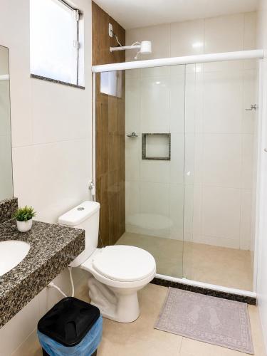 a bathroom with a toilet and a glass shower at Pousada Viva Mar in Saquarema