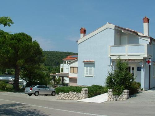 a white house with a car parked in front of it at Charming apartment in Kampor with private garden - 28 m² in Kampor