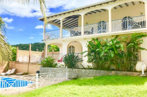 a house with a balcony and a swimming pool at Spacieuse villa à Deshaies avec piscine privée in Deshaies
