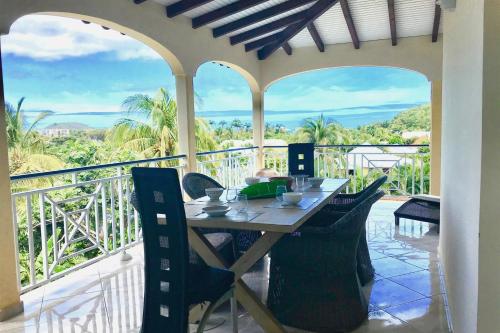 a table and chairs on the balcony of a house at Spacieuse villa à Deshaies avec piscine privée in Deshaies