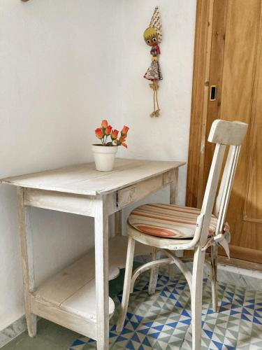 a white desk with a chair and a vase of flowers at Charming Apartment in Albuñol, 90 m², Near Amenities in Albuñol