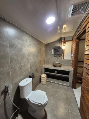 a bathroom with a white toilet and a mirror at Snuggy Hostel Kuta in Kuta Lombok