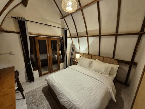 a bedroom with a white bed in a room with a window at Snuggy Hostel Kuta in Kuta Lombok