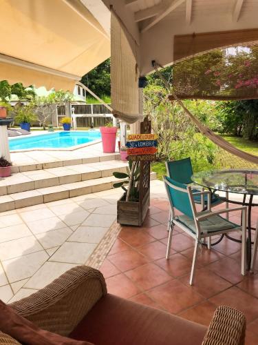 a patio with a table and chairs and a pool at Studio cosy aux Abymes, piscine et jardin, 25 m² in Les Abymes
