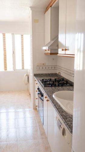 a white kitchen with a sink and a stove at Apartment with pool in Águilas 75 m² with sea view in Águilas