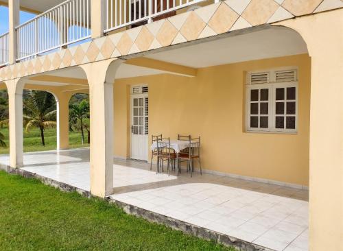 a patio with a table and a balcony at Appartement spacieux au Vauclin de 150 m² avec vue montagne in Le Vauclin
