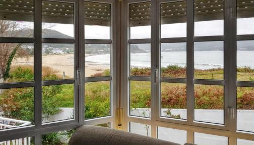 a room with four windows looking out at the ocean at Comfortable house with sea view in Viveiro, 200 m² in Viveiro