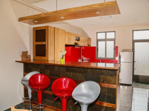 a kitchen with red stools at a counter at Luxurious Villa in Pereybere with Pool in Pereybere