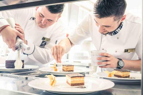 a couple of chefs preparing food in a kitchen at Hotel Radun in Luhačovice