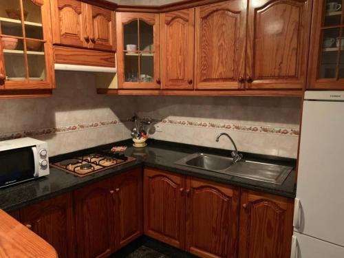 a kitchen with wooden cabinets and a sink at Cozy apartment with sea view in Frontera in Frontera
