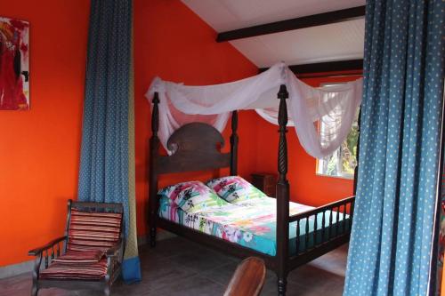 a bedroom with a bed with an orange wall at Bungalow charmant avec vue sur la mer à Sainte Rose in Sainte-Rose