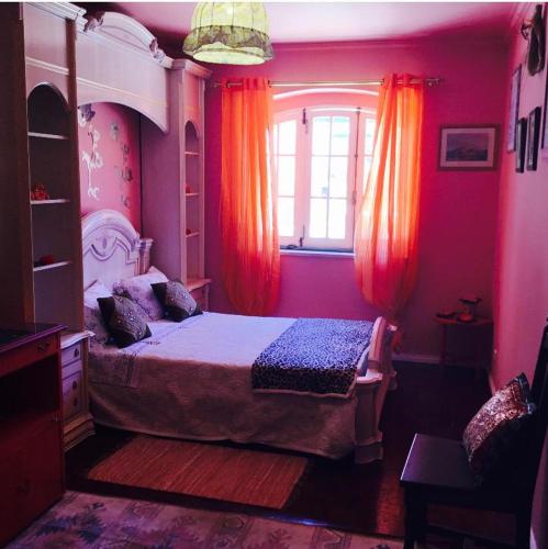 a bedroom with a bed and a window with orange curtains at Spacious Apartment Sintra 120 m² + Pool in Sintra