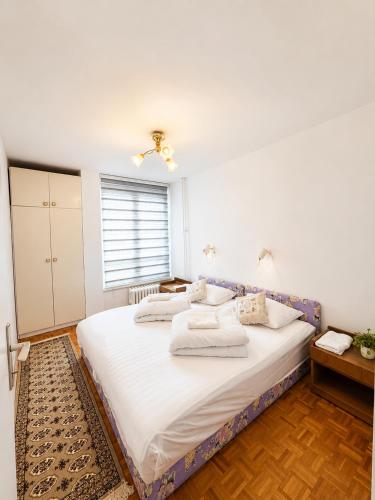a bedroom with a large bed with white sheets and pillows at Riverside Apartment, 10min Airport in Sarajevo