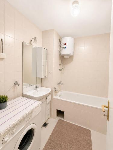 a white bathroom with a tub and a sink and a washing machine at Riverside Apartment, 10min Airport in Sarajevo