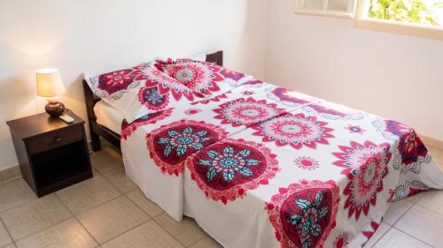 a bedroom with a bed with a red and white blanket at Maison accueillante à Anse-Bertrand avec jardin privé 70 m² in Anse-Bertrand