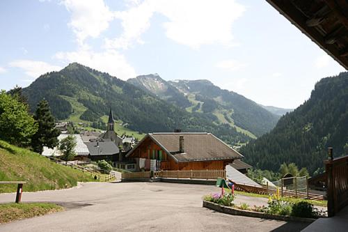 a building on a hill with mountains in the background at Appartement spacieux à Châtel 120 m² avec terrasse privée in Châtel