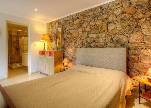 a bedroom with a stone wall with a bed at Studio accueillant à Moltifao 30 m² avec terrasse et jardin in Moltifao