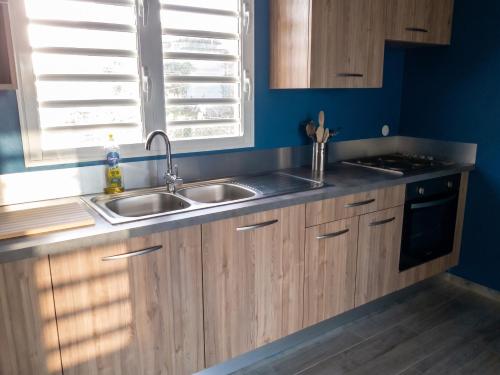 a kitchen with wooden cabinets and a sink and a window at Villa charmante au Moule avec piscine in Le Moule
