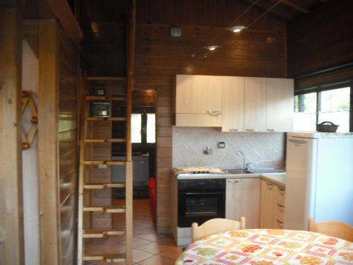 a small kitchen with a refrigerator and a table at Comfortable Chalet in Giarola with Mountain View in Busana