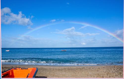 a rainbow over the beach with a boat in the water at Appartement cosy au Carbet avec balcon et vue sur mer - 70 m² in Le Carbet