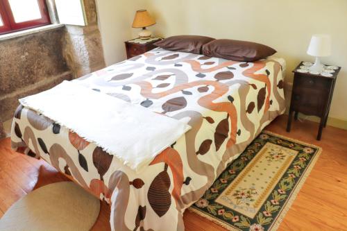 a bedroom with a bed with a brown and white comforter at Cozy House in Seia with Fireplace in Faia
