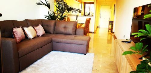 a living room with a brown couch with pillows at Spacious apartment in La Cala de Mijas with sea view. in La Cala de Mijas