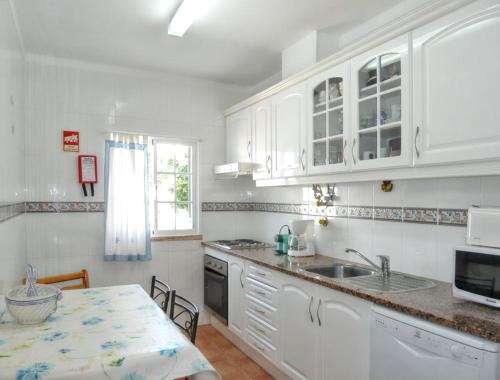 a kitchen with white cabinets and a sink and a table at Charming house in Vila Nova de Cacela with garden in Vila Nova De Cacela