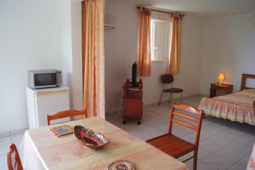 a room with two beds and a table and chairs at Studio cosy au Moule 30 m² avec jardin privé in Le Moule