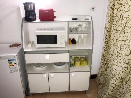 a small kitchen with a microwave and a refrigerator at Studio chaleureux à Sainte-Anne - 29m² avec jardin. in Sainte-Anne
